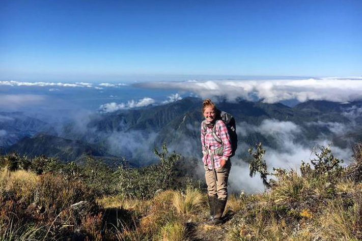 A hiker in a high-altitude landscape above the clouds, highlighting rugged terrain.