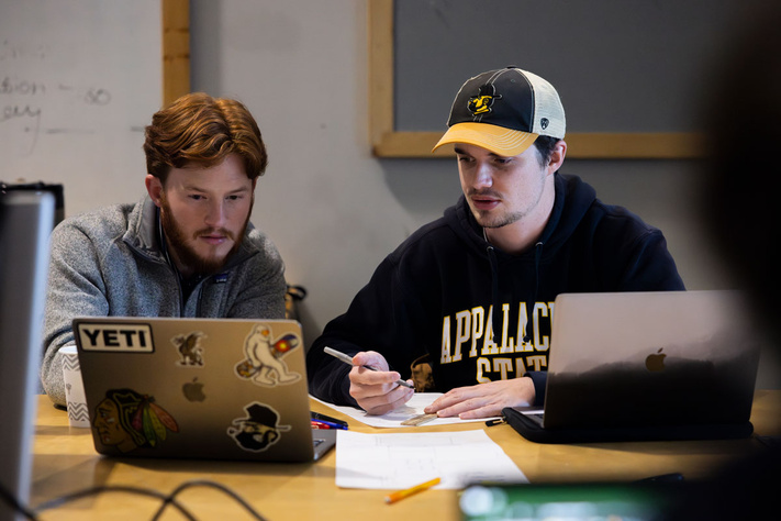Two students working on laptop