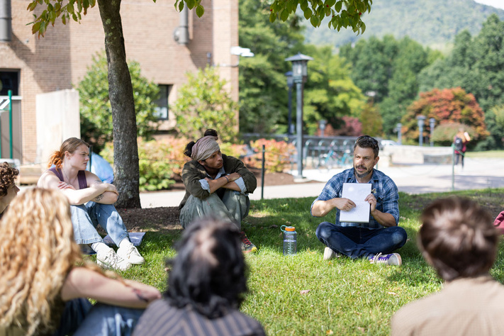 Class seated in a circle outside with instructor