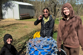 App State students stand outside around a rain barrel, an elephant enrichment activity at the Animal Sanctuary.