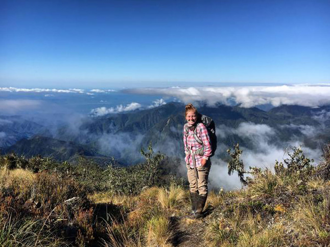 A hiker in a high-altitude landscape above the clouds, highlighting rugged terrain